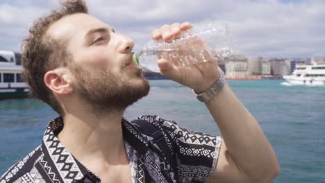 Man-drinking-water-on-the-beach-by-the-sea.